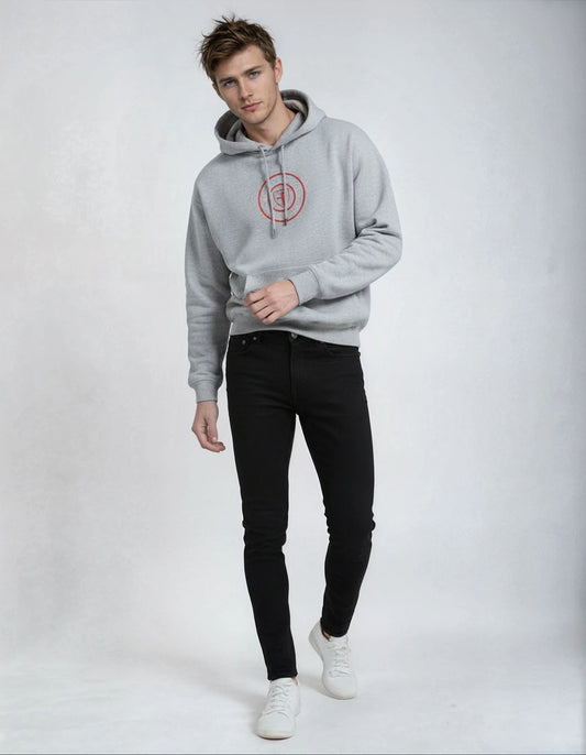 Man wearing a gray paganus hoodie with a red logo and black pants on a white background