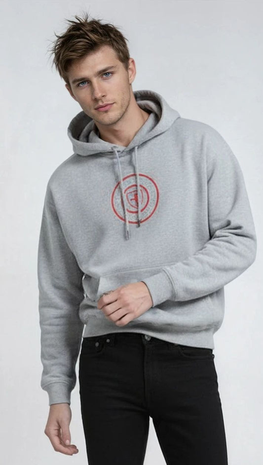 Man wearing a gray paganus hoodie with a red logo and black pants on a white background