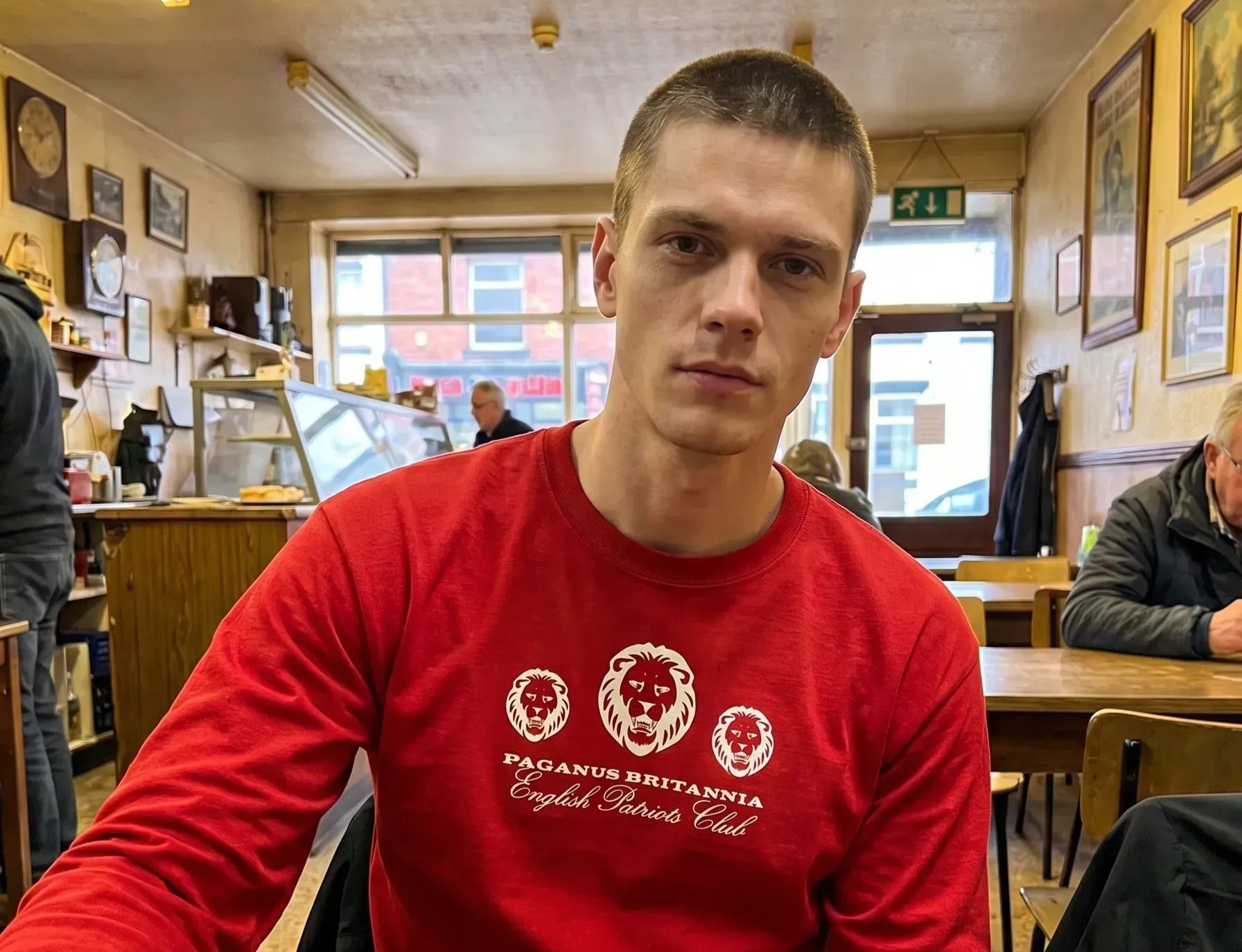 Man wearing a red sweatshirt with a logo in a casual setting