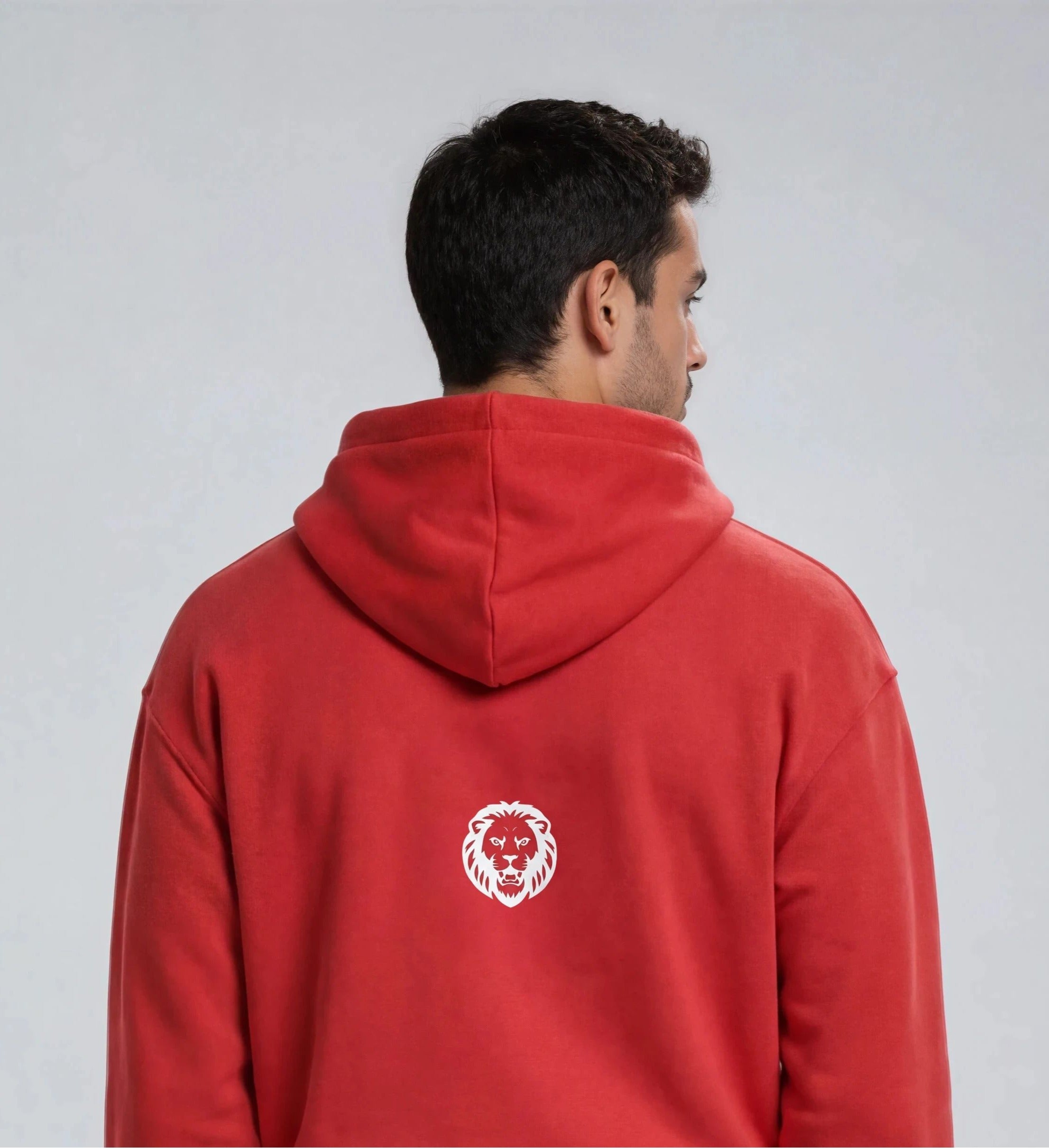 Person wearing a red hoodie with a lion logo on the back against a gray background