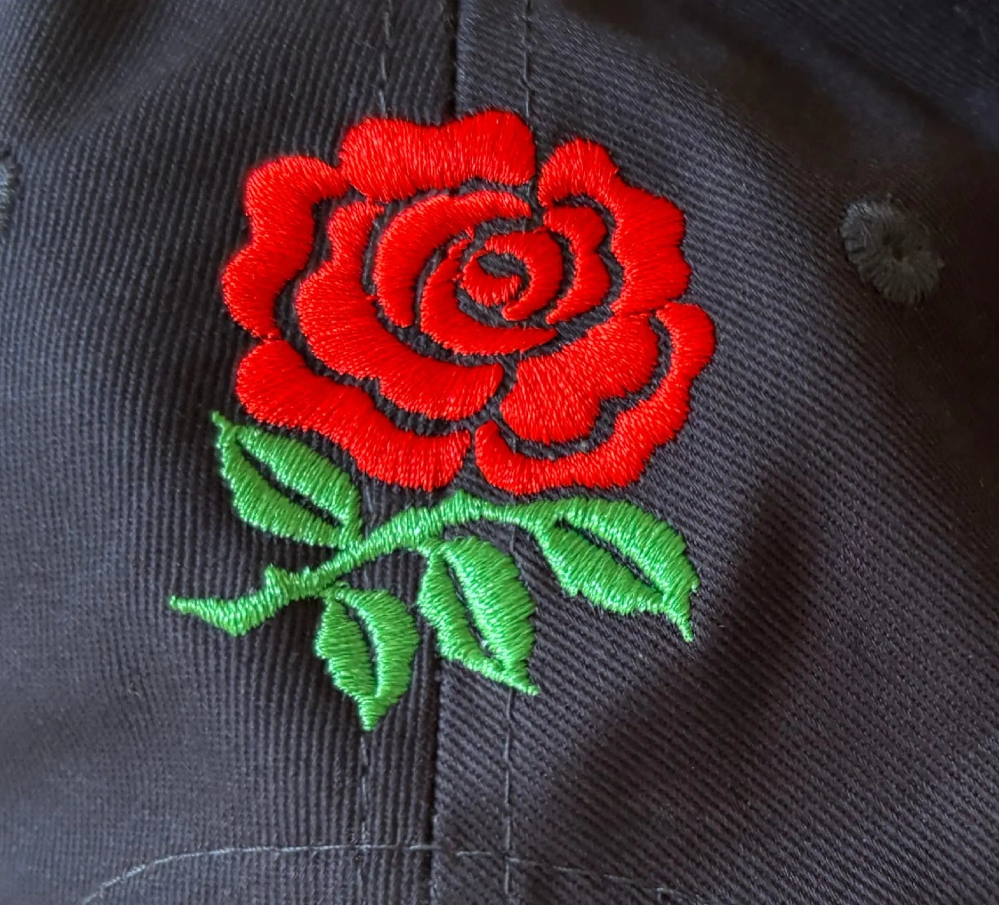 Red English rose embroidered on a dark blue baseball cap