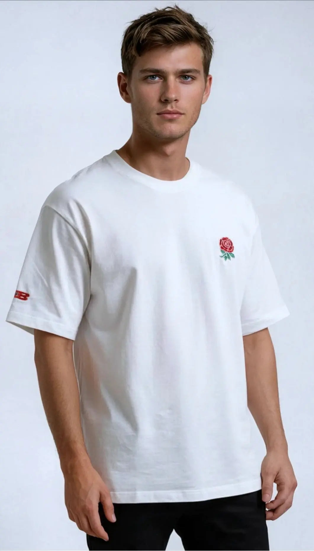 Man wearing a white paganus t-shirt with a red rose emblem on a light gray background