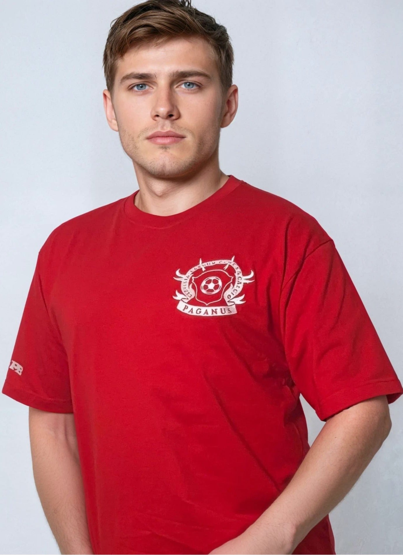 Man wearing a red t-shirt with a logo on a light gray background