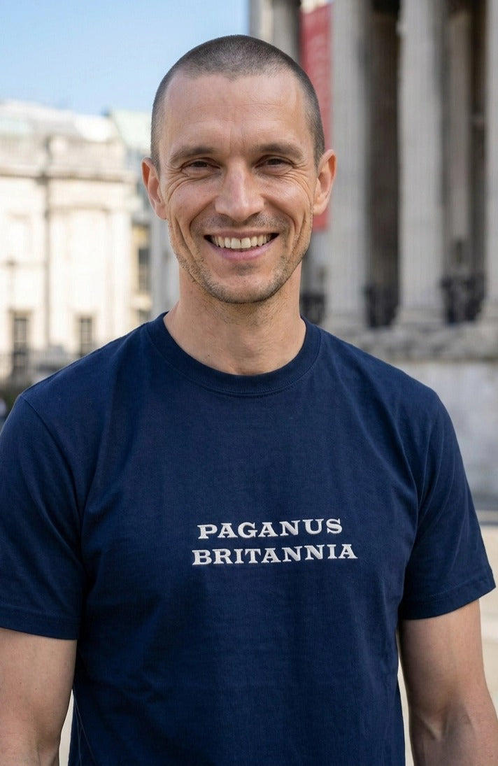Man wearing a navy blue t-shirt with 'PAGANUS BRITANNIA' text, standing outdoors.