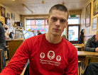 Man wearing a red sweatshirt with a logo in a casual setting
