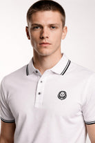 Man wearing a white polo shirt with a logo on a white background