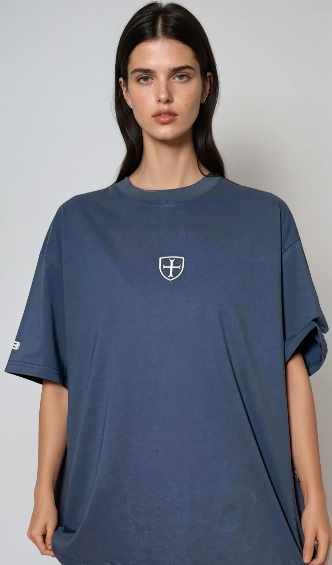 Woman wearing a blue t-shirt with a logo on a plain background