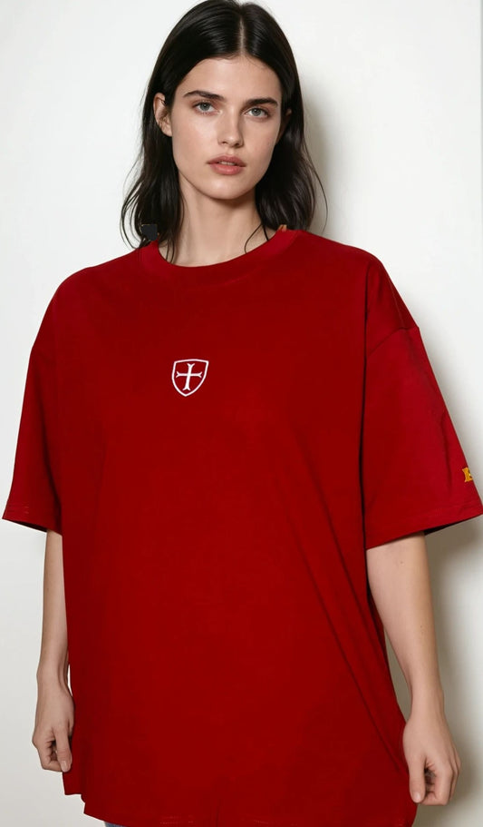 Person wearing a red oversized t-shirt with a small logo on a white background