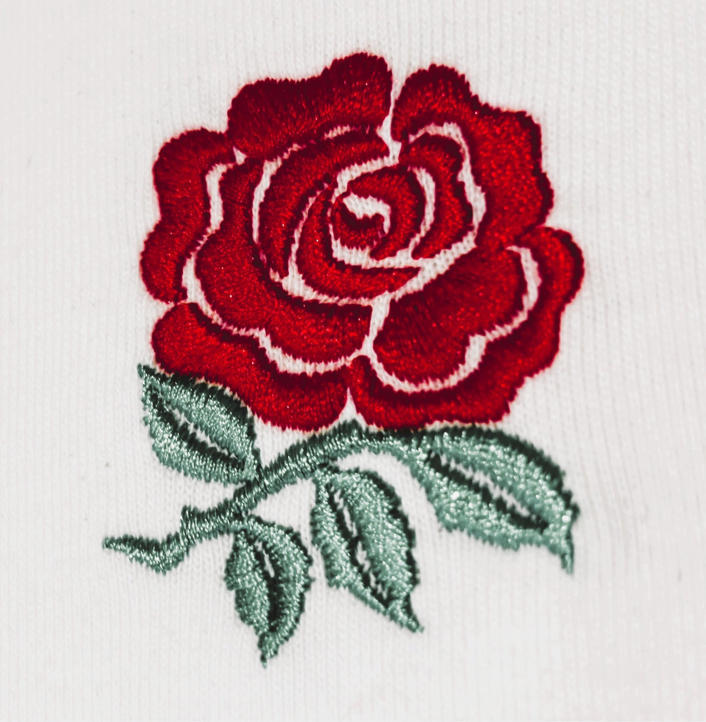 Embroidered red rose with green leaves on a white background