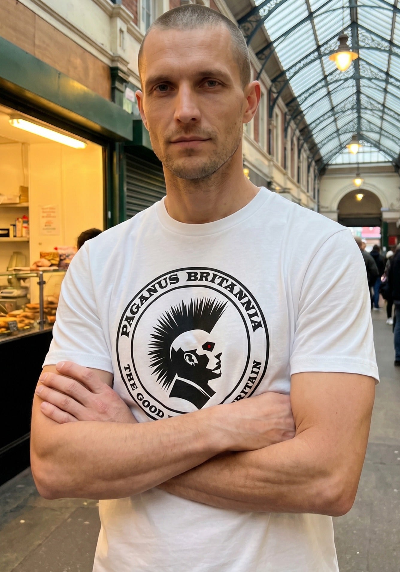 Man wearing a white t-shirt with a logo and text in an indoor setting