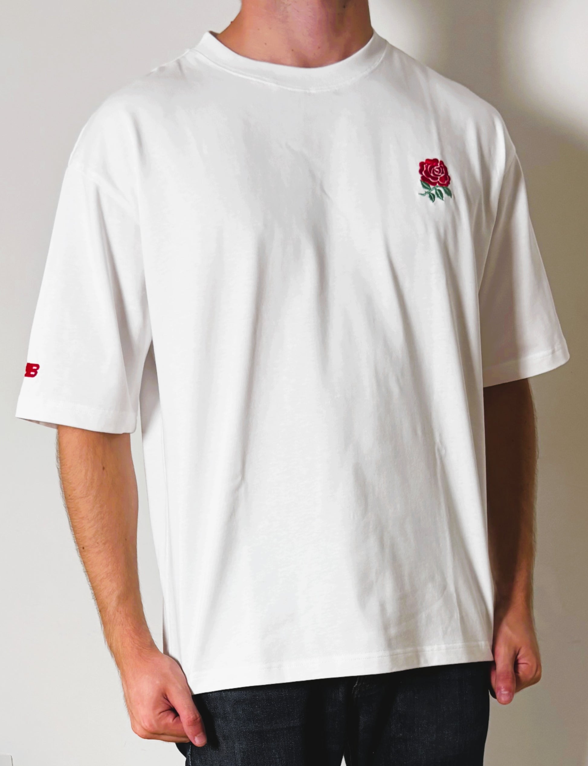 Person wearing a white t-shirt with a red rose design on a plain background
