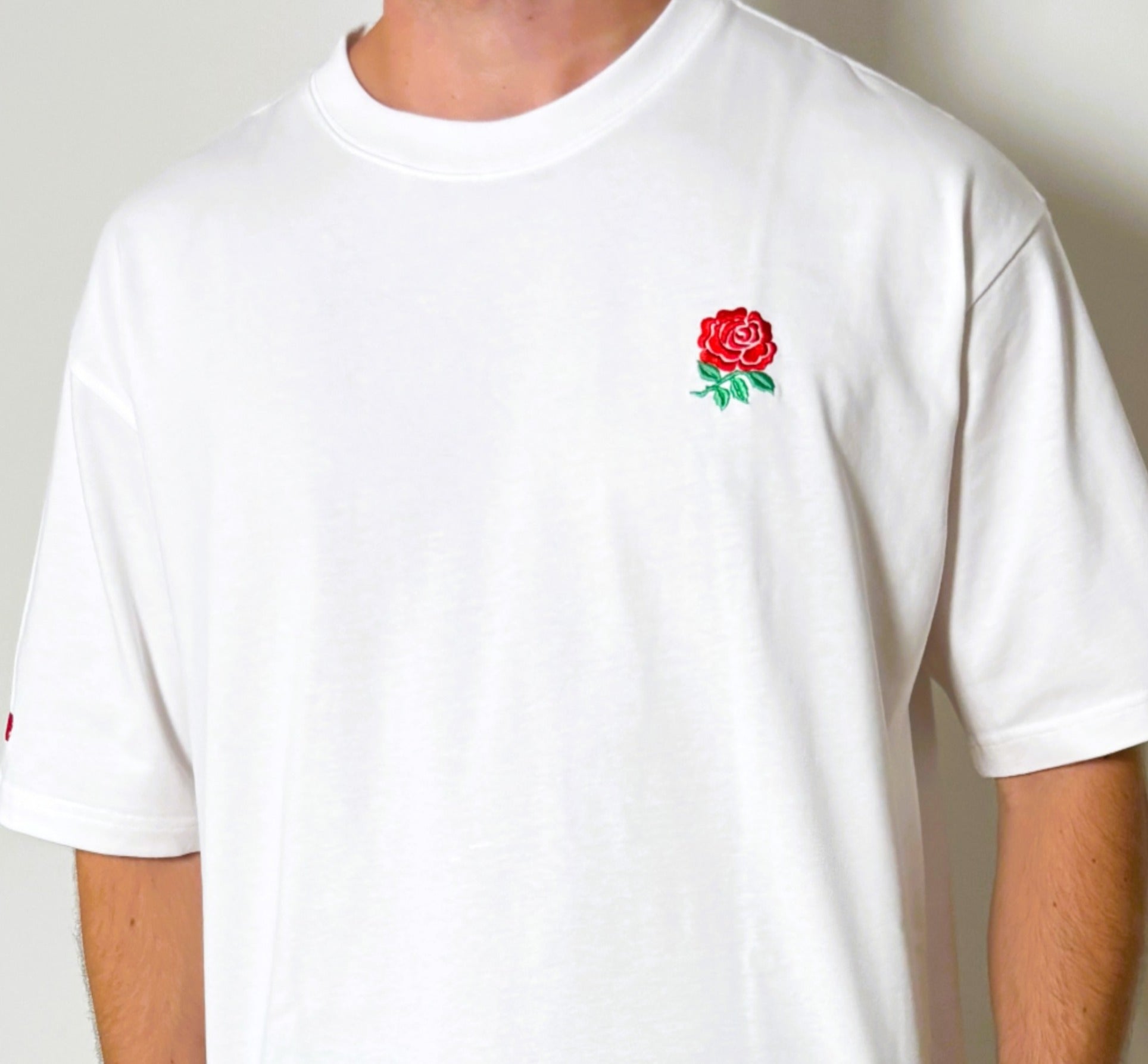 White t-shirt with a red rose logo on a plain background