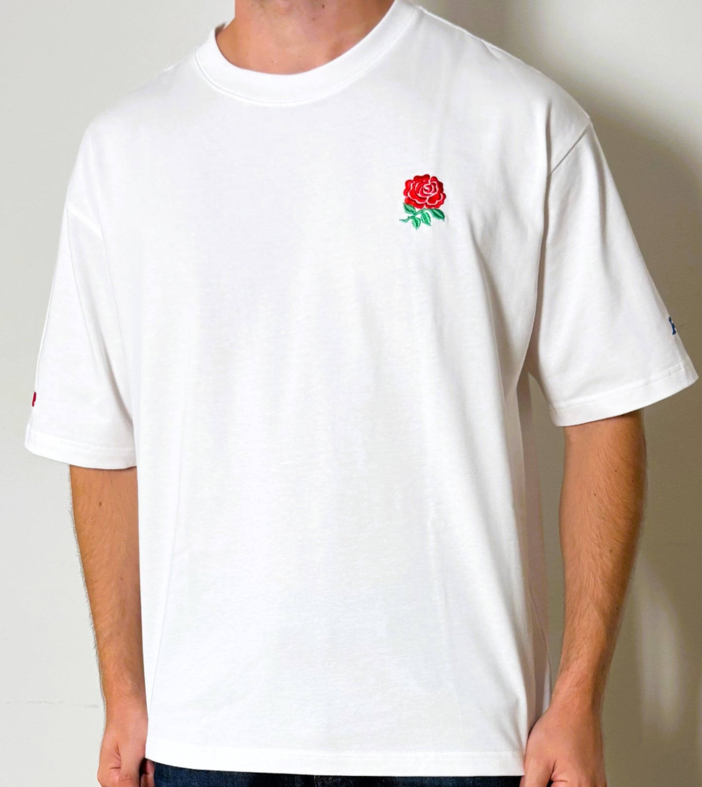 White t-shirt with a red rose emblem on a plain background