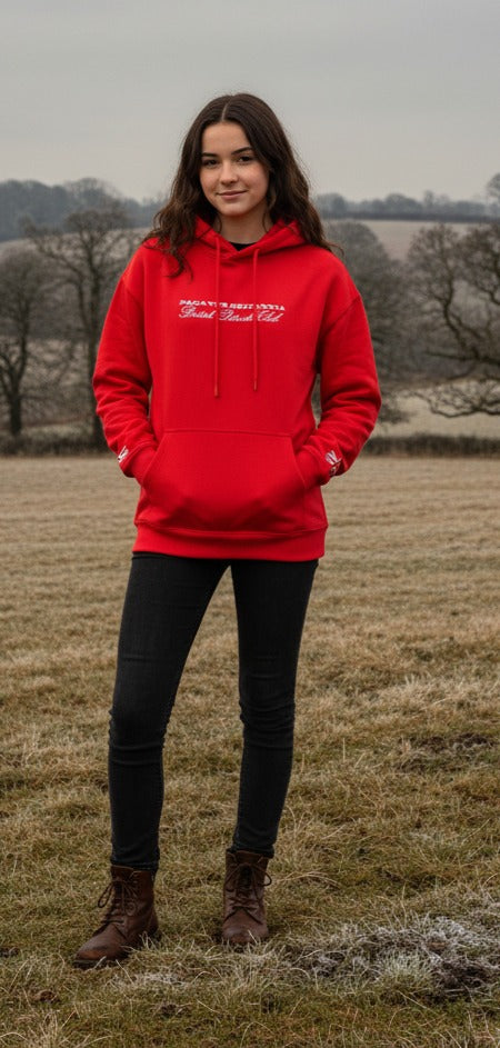 Person wearing a PAGANUS BRITANNIA red hoodie with text standing in a field IN Yorkshire
