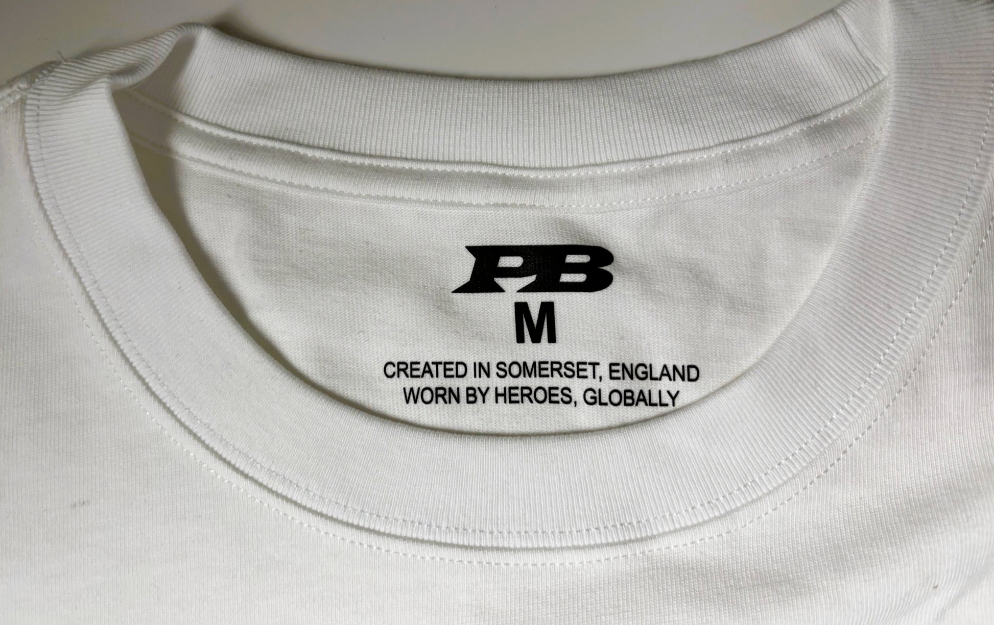 Man wearing a white 280 gsm t-shirt with a blue logo 