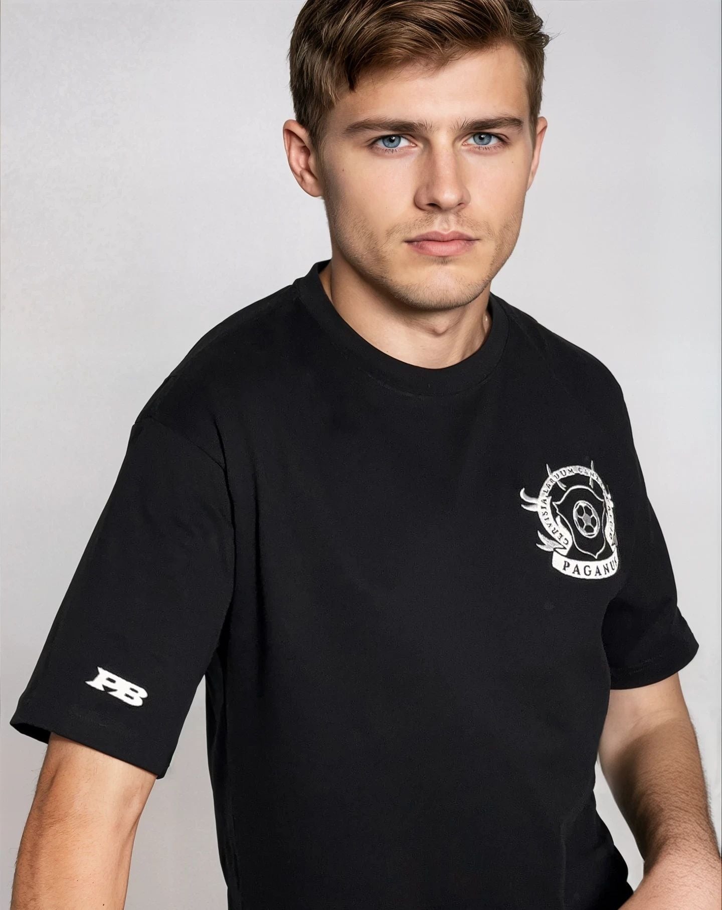 Man wearing a black t-shirt with logos on a plain background